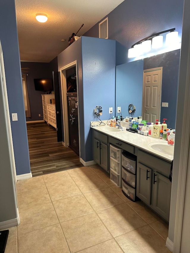 bathroom with dual vanity, a textured ceiling, and tile floors