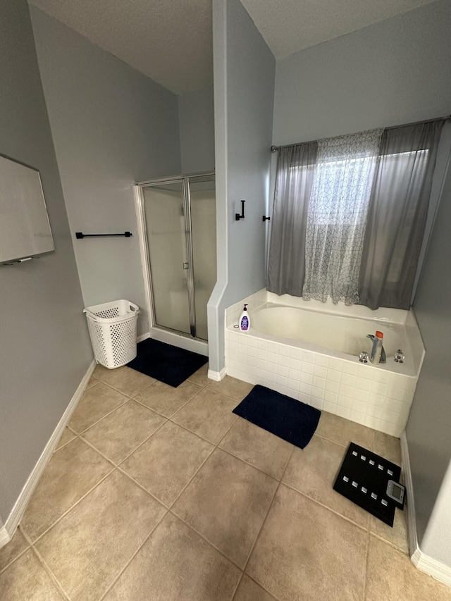 bathroom featuring a stall shower, tile patterned flooring, baseboards, and a garden tub