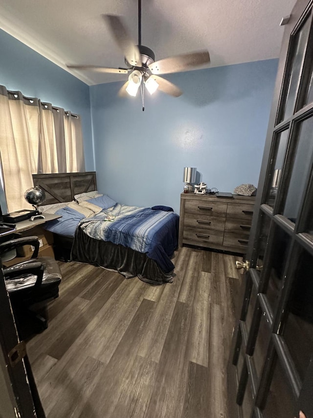 bedroom with ceiling fan, a textured ceiling, and dark wood-type flooring