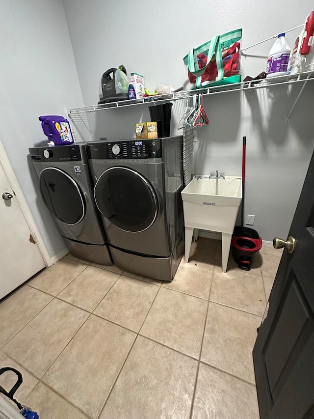 clothes washing area with independent washer and dryer, sink, and light tile flooring