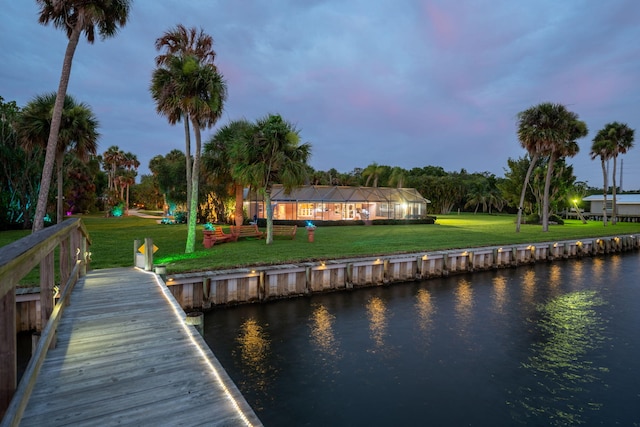 view of dock with a lawn and a water view