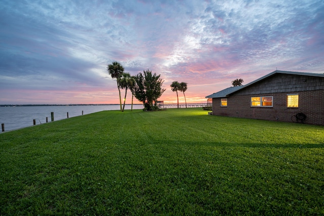 yard at dusk featuring a water view