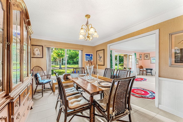 tiled dining area with a notable chandelier, ornamental molding, and a textured ceiling