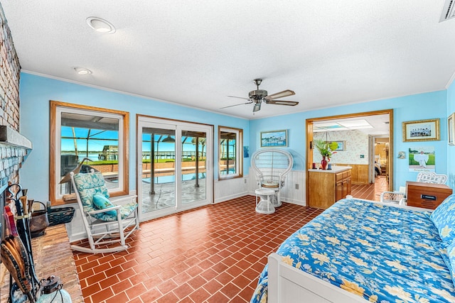 bedroom featuring ceiling fan, access to exterior, a large fireplace, and a textured ceiling