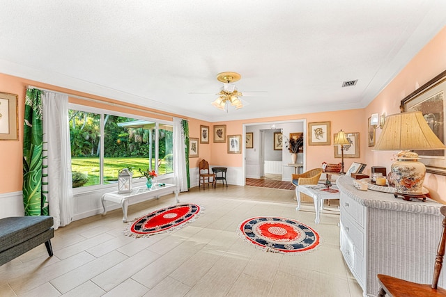 living room featuring ceiling fan, crown molding, and a textured ceiling