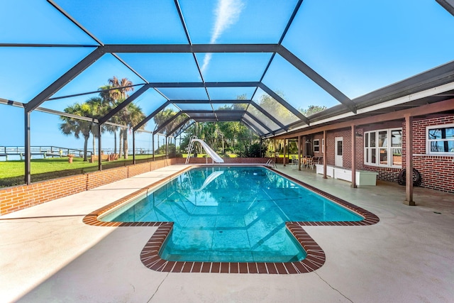 view of pool featuring a patio, a water slide, and glass enclosure