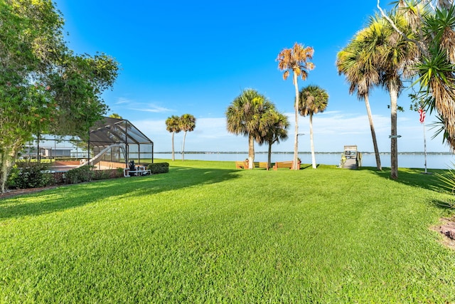 view of yard with a water view and glass enclosure