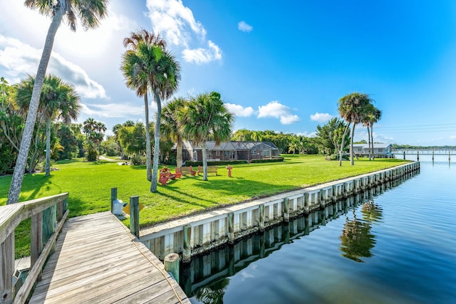 view of dock with a lawn and a water view