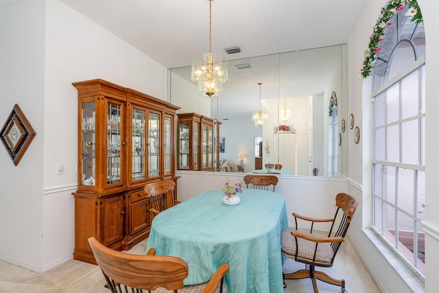 carpeted dining area with a chandelier