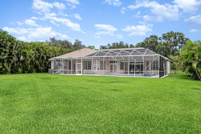 rear view of property with glass enclosure and a lawn