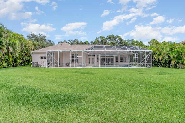 rear view of property with a lanai, central air condition unit, and a yard