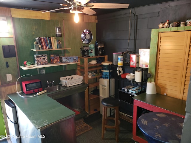 kitchen featuring ceiling fan, wooden walls, and sink