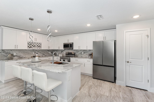 kitchen featuring white cabinets, decorative light fixtures, light stone counters, and stainless steel appliances