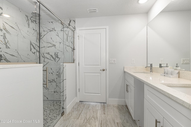 bathroom with vanity, an enclosed shower, and a textured ceiling