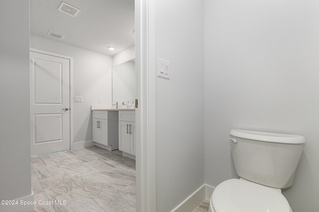 bathroom with vanity, toilet, and a textured ceiling