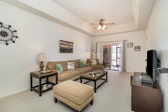 living room featuring ceiling fan, light carpet, and a tray ceiling