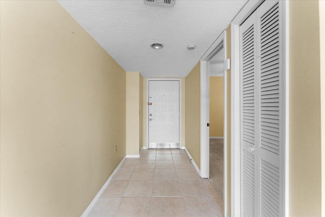 hall featuring light tile patterned floors and a textured ceiling