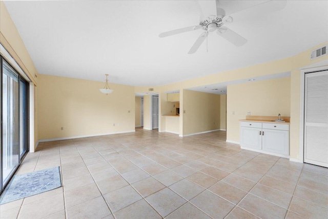 unfurnished living room with ceiling fan, light tile patterned flooring, a healthy amount of sunlight, and sink