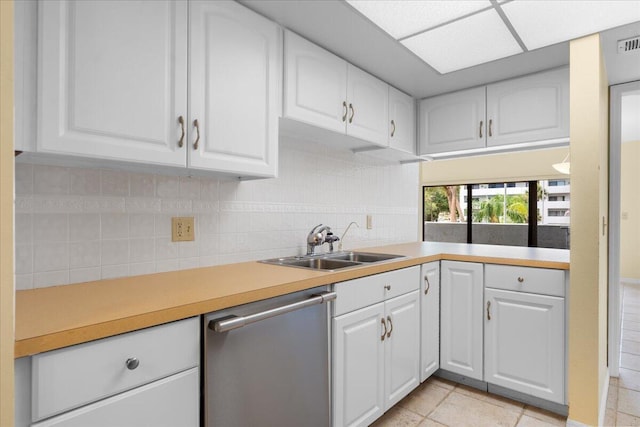 kitchen with backsplash, white cabinets, sink, light tile patterned floors, and dishwasher