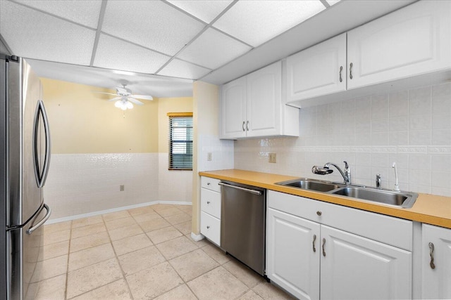 kitchen with ceiling fan, sink, a drop ceiling, white cabinets, and appliances with stainless steel finishes