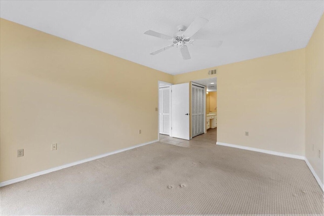 unfurnished bedroom with ceiling fan, light carpet, and ensuite bath