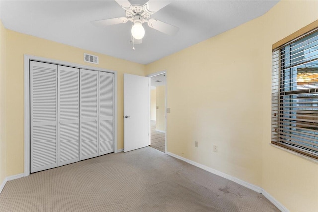 unfurnished bedroom featuring ceiling fan, light colored carpet, and a closet