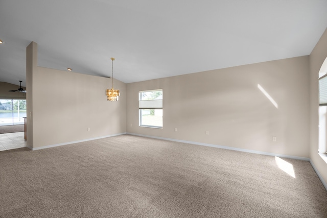 carpeted spare room with ceiling fan with notable chandelier and vaulted ceiling