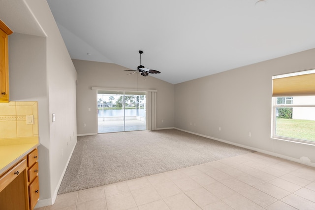 unfurnished living room featuring ceiling fan, light colored carpet, and vaulted ceiling