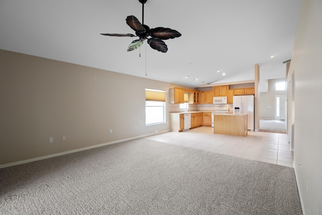 kitchen with lofted ceiling, white appliances, light carpet, ceiling fan, and light brown cabinetry