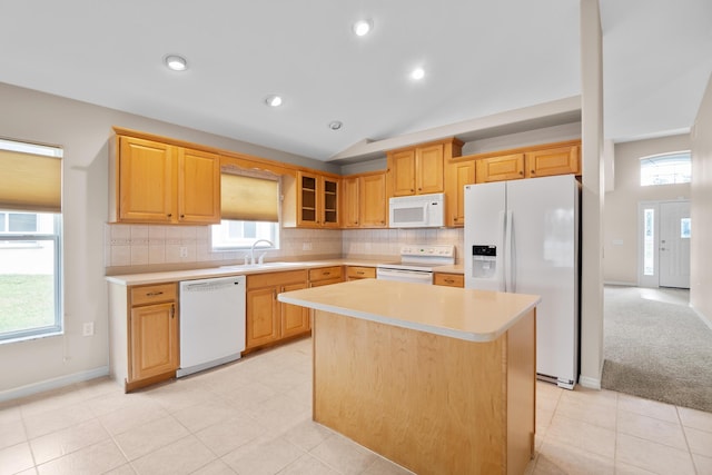 kitchen with lofted ceiling, plenty of natural light, a center island, and white appliances