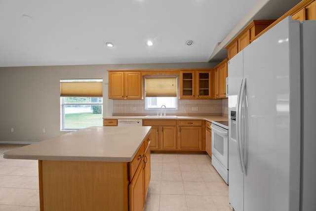 kitchen with decorative backsplash, white appliances, a center island, and sink