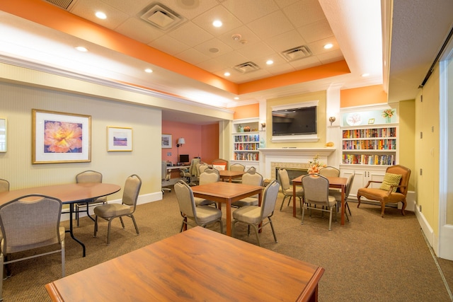 dining room with a raised ceiling, dark carpet, and built in shelves