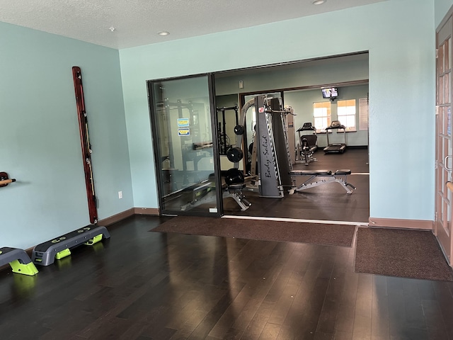 exercise room with hardwood / wood-style floors and a textured ceiling