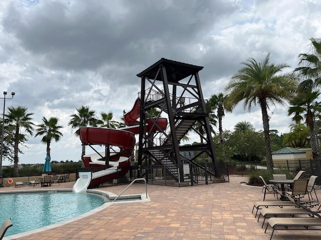 view of pool with a playground, a patio, and a water slide