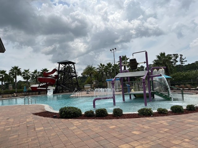 view of pool with pool water feature, a playground, and a water slide