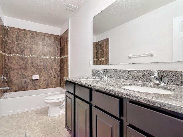 full bathroom featuring tiled shower / bath, vanity, toilet, tile patterned floors, and a textured ceiling