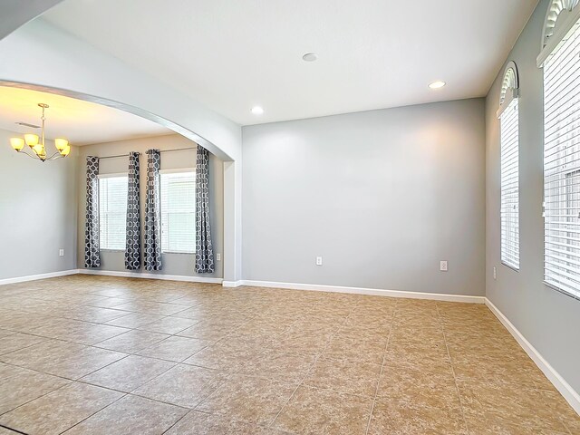 tiled empty room featuring a chandelier