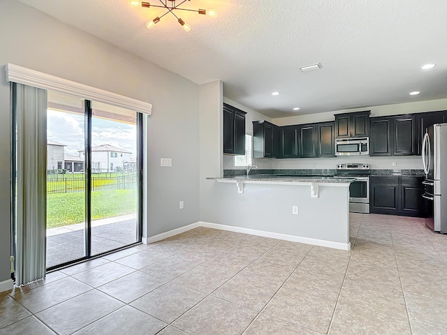 kitchen featuring a breakfast bar, sink, light tile patterned floors, kitchen peninsula, and stainless steel appliances