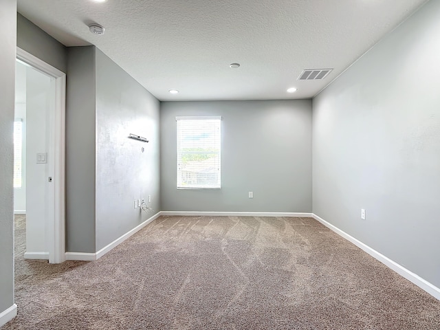 empty room with carpet floors and a textured ceiling