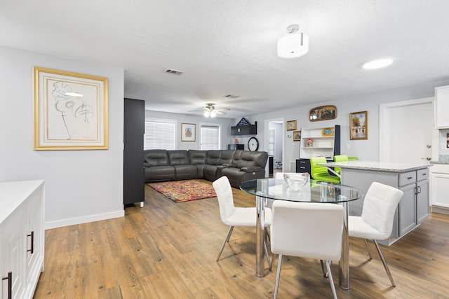 dining space with ceiling fan, light hardwood / wood-style floors, and a textured ceiling