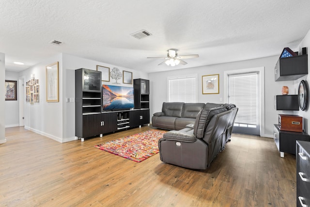 living room featuring a textured ceiling, light hardwood / wood-style flooring, and ceiling fan