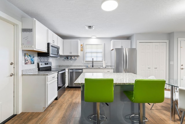 kitchen featuring sink, a center island, white cabinets, and appliances with stainless steel finishes