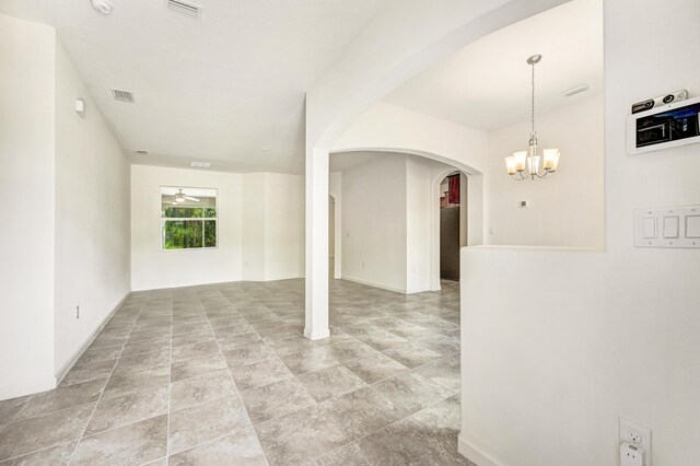 empty room with ceiling fan with notable chandelier