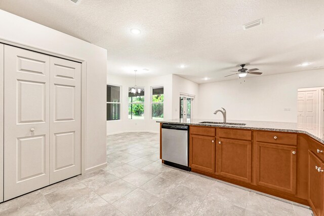 kitchen featuring ceiling fan with notable chandelier, dishwasher, sink, light stone countertops, and a textured ceiling