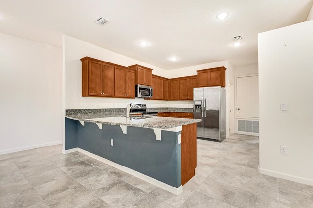 kitchen featuring sink, a breakfast bar area, light stone counters, appliances with stainless steel finishes, and kitchen peninsula