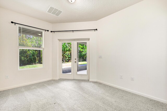 carpeted spare room featuring french doors and a textured ceiling