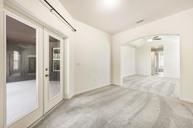 carpeted empty room with ceiling fan, a textured ceiling, and french doors