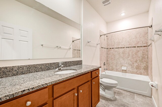 full bathroom featuring vanity, tiled shower / bath combo, and toilet