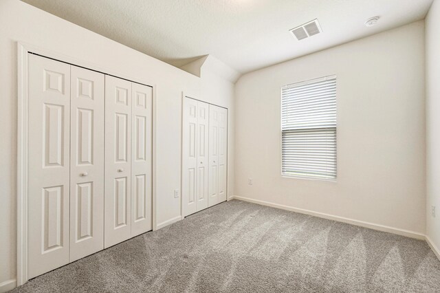 unfurnished bedroom with two closets and carpet floors