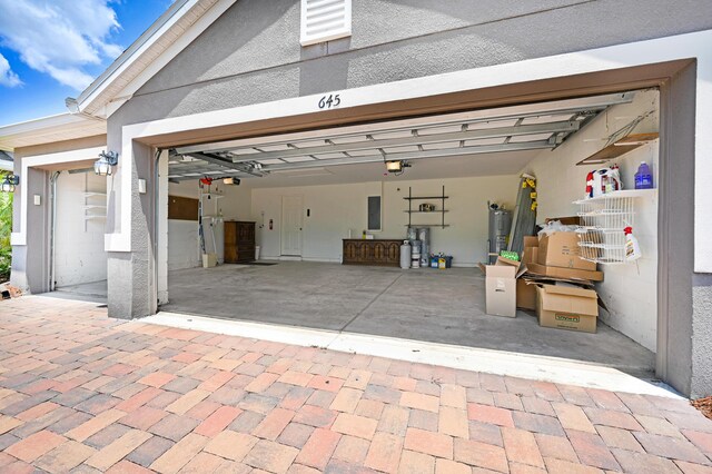 garage featuring a garage door opener, electric panel, and water heater